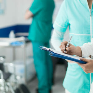 Medical staff working at the hospital: doctor and nurse checking a patient's medical record on a clipboard, healthcare and medical exams concept