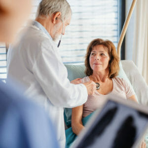 A senior doctor and nurse examining a woman patient in hospital.